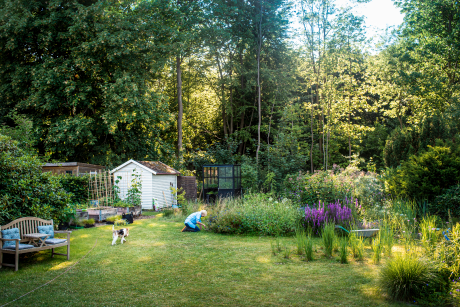 Ein großer Garten mit Sitzbank, Gartenhäuschen und Beeten