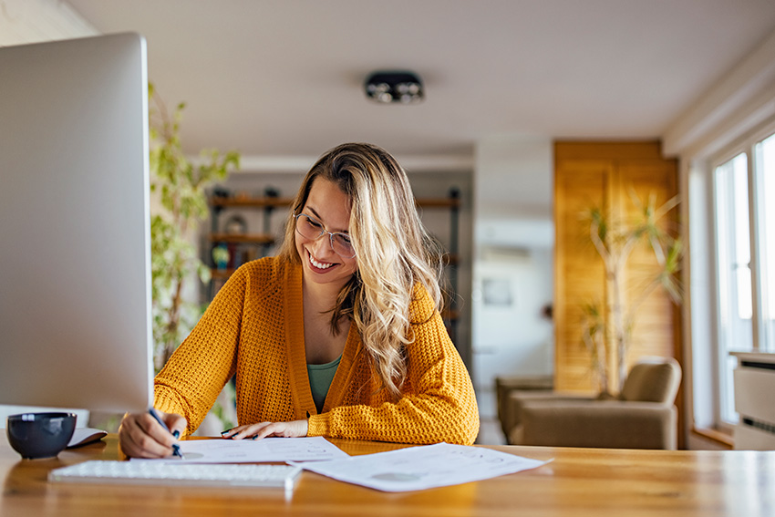 Frau sitzt am Schreibtisch und füllt ein Formular aus.