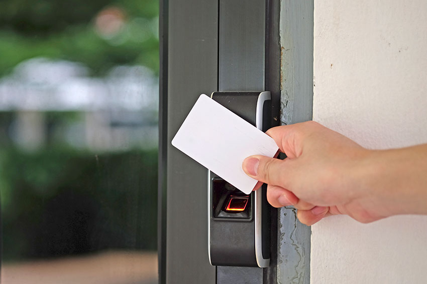 Eine Hand öffnet mit einer Schlüsselkarte ein Türschloss.