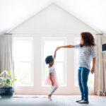 Frau tanzt mit Kind auf dem ausgebauten Dachboden.