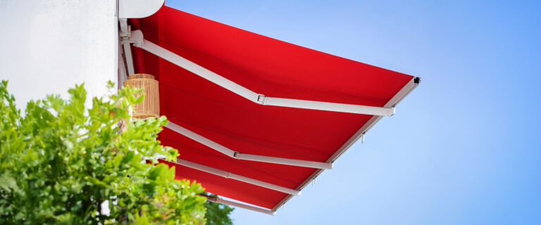 Rote Markise vor blauem Himmel.